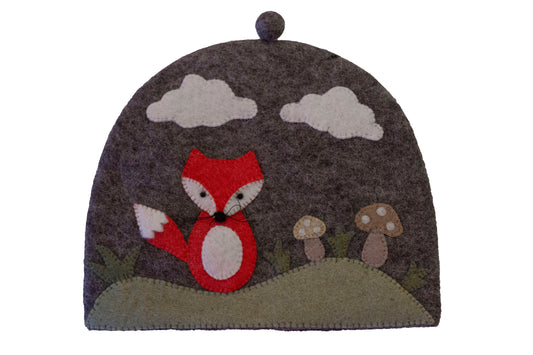 This Global Groove Life, handmade, Fair Trade, 100% New Zealand Wool, grey and orange Felt Tea Cozy with mushroom, cloud and fox motif, will keep your tea warm on chilly mornings and brighten your kitchen with color and whimsy.